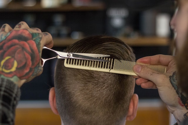 coiffeur coupant des cheveux avec un peigne et un ciseau